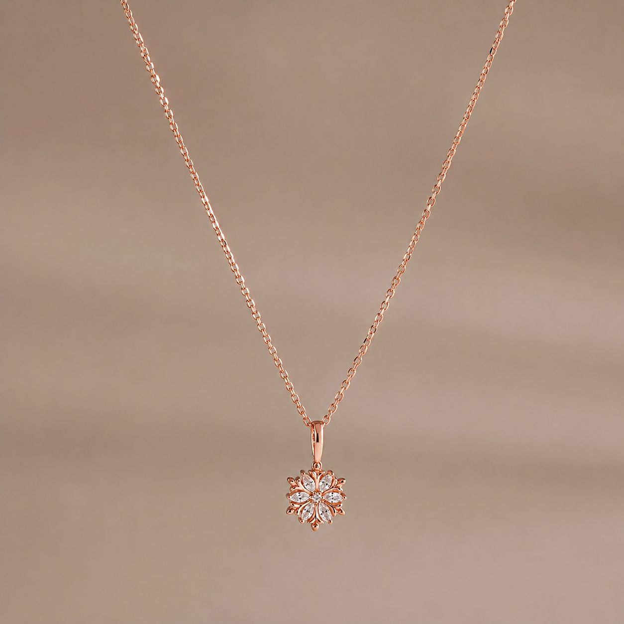 Rose gold necklace with a snowflake pendant on a brown background